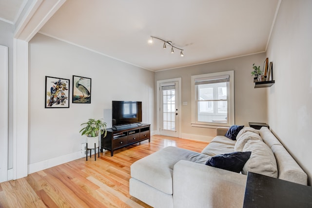 living area with crown molding, baseboards, and wood finished floors