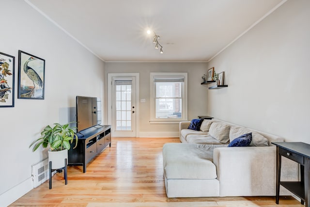 living area with ornamental molding, light wood-style flooring, and baseboards