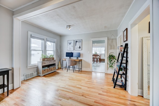 office area with a healthy amount of sunlight, crown molding, visible vents, and wood finished floors