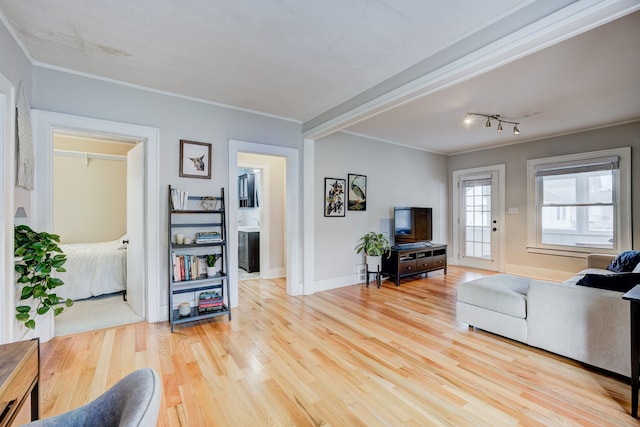 living room with crown molding, baseboards, and wood finished floors