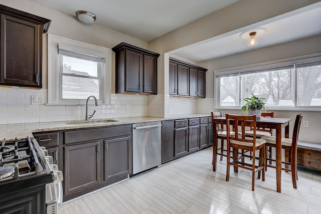 kitchen with tasteful backsplash, a sink, stainless steel dishwasher, and dark brown cabinets