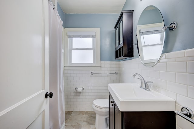 full bath with tile walls, toilet, wainscoting, vanity, and tile patterned floors