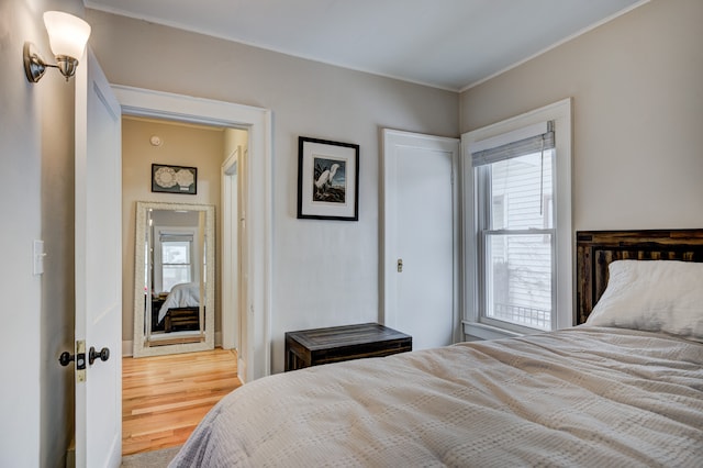 bedroom with ornamental molding and wood finished floors