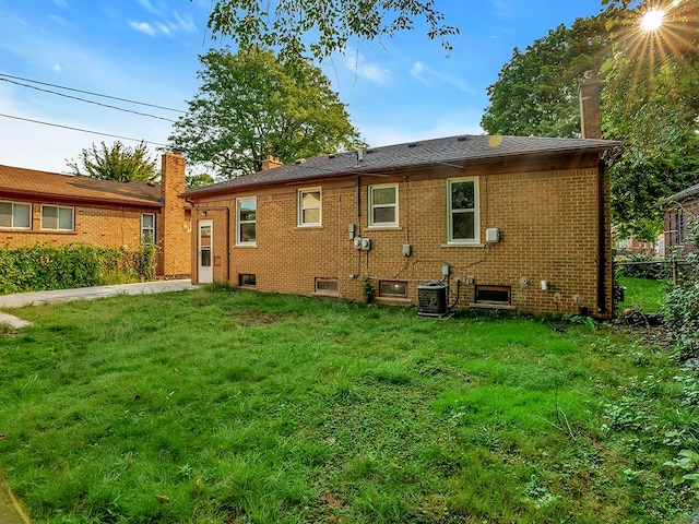 back of property with cooling unit and a yard