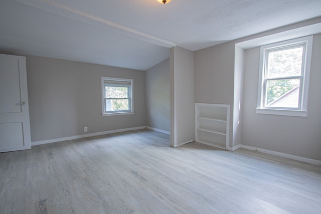 additional living space featuring lofted ceiling and light hardwood / wood-style flooring