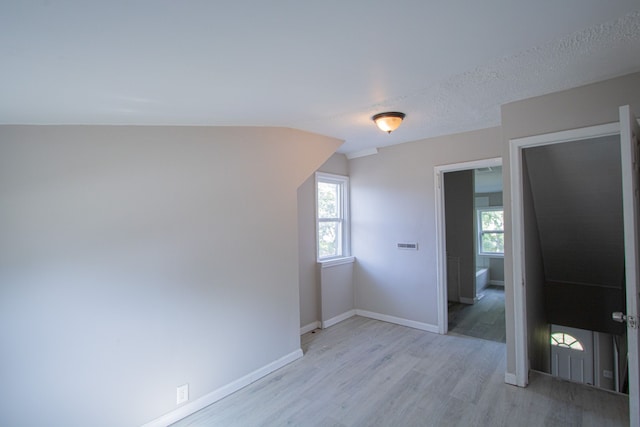 additional living space featuring light hardwood / wood-style floors and a textured ceiling