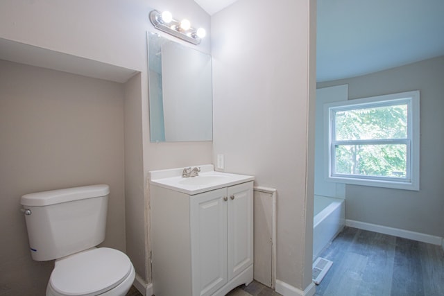 bathroom featuring hardwood / wood-style flooring, vanity, a bathtub, and toilet