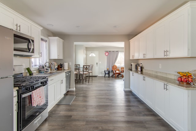 kitchen with appliances with stainless steel finishes, dark hardwood / wood-style floors, white cabinets, and plenty of natural light