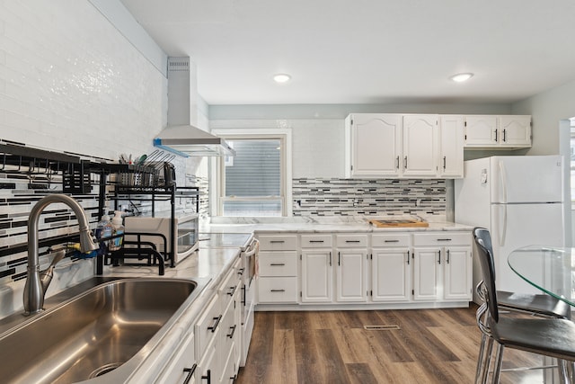 kitchen with dark wood-type flooring, wall chimney exhaust hood, sink, white appliances, and white cabinets