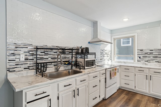 kitchen featuring wall chimney range hood, white appliances, sink, white cabinetry, and decorative backsplash