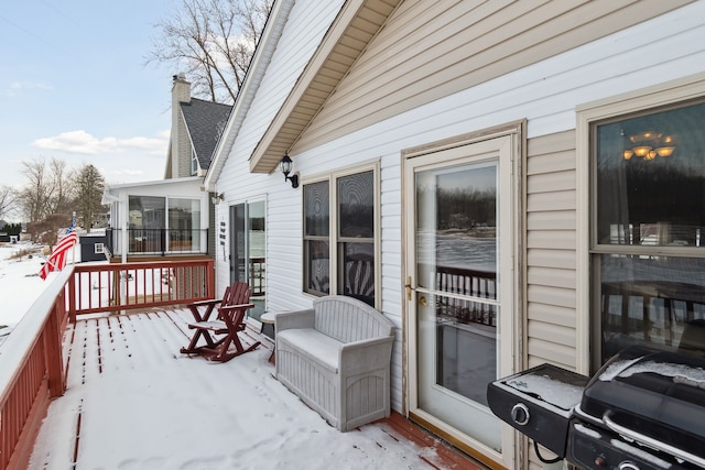 snow covered deck featuring a sunroom