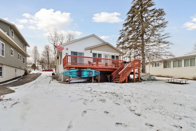 snow covered back of property with a deck