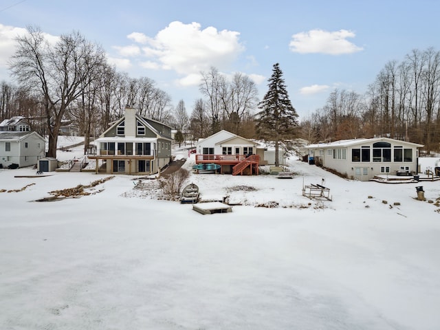 snow covered house featuring a sunroom and a deck