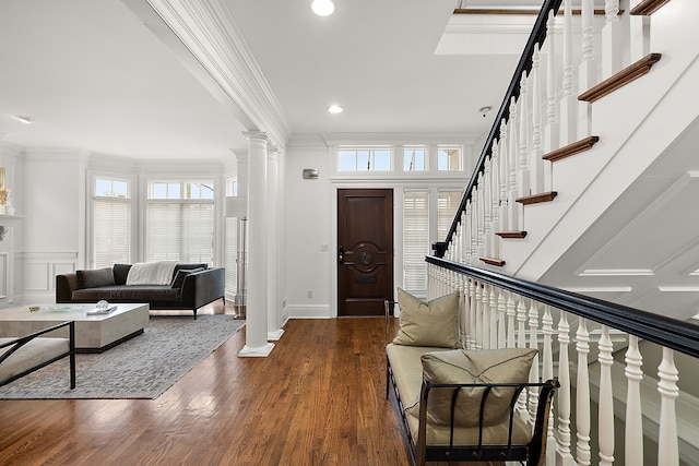 entryway featuring decorative columns, ornamental molding, and dark wood-type flooring