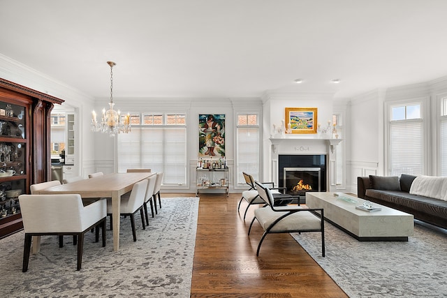 dining area with dark wood-type flooring, ornamental molding, and an inviting chandelier