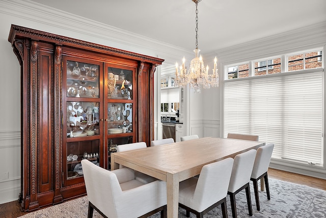 dining room with crown molding, hardwood / wood-style flooring, and an inviting chandelier