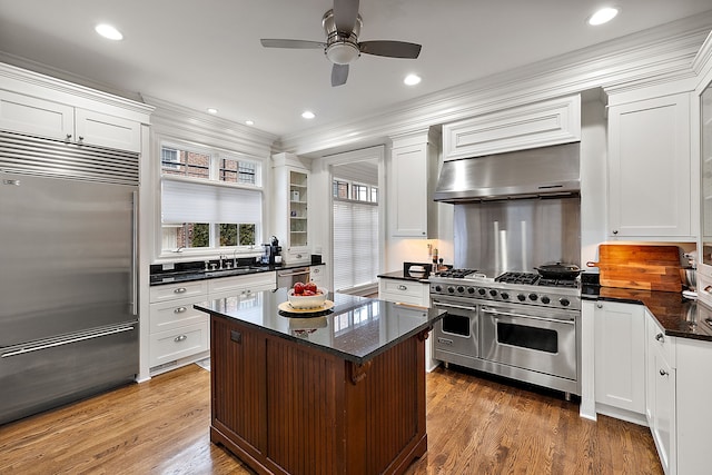 kitchen with high end appliances, wood-type flooring, white cabinets, and a kitchen breakfast bar