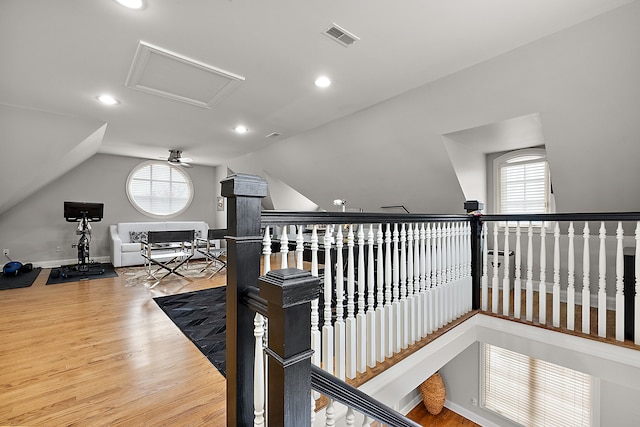 hall featuring lofted ceiling, a healthy amount of sunlight, and hardwood / wood-style floors