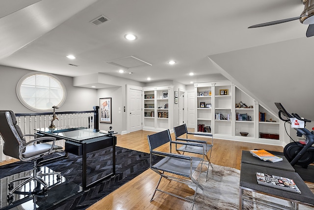 living room featuring ceiling fan, light wood-type flooring, and built in shelves