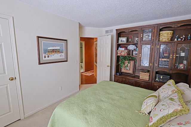 bedroom featuring light carpet and a textured ceiling