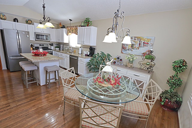 dining space with sink, dark hardwood / wood-style floors, vaulted ceiling, and a textured ceiling