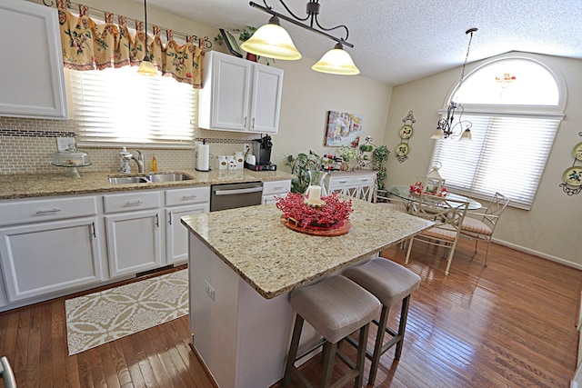 kitchen featuring sink, decorative light fixtures, a center island, and white cabinets