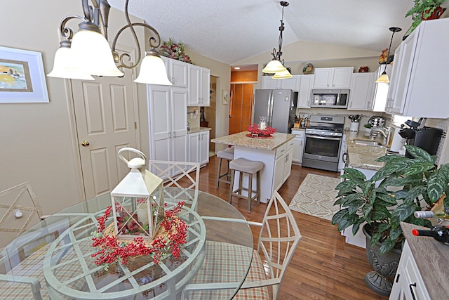 kitchen featuring sink, a breakfast bar area, white cabinetry, a center island, and appliances with stainless steel finishes