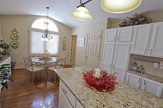 kitchen featuring white cabinetry, vaulted ceiling, dark hardwood / wood-style flooring, pendant lighting, and decorative backsplash