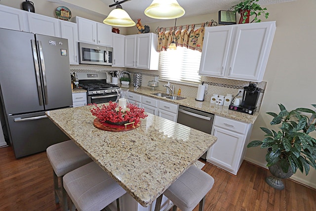 kitchen featuring a kitchen island, pendant lighting, sink, white cabinets, and stainless steel appliances