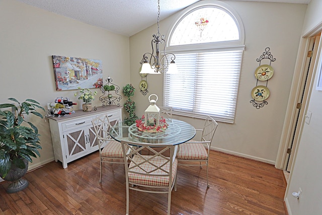 dining area featuring lofted ceiling, dark hardwood / wood-style flooring, a textured ceiling, and a notable chandelier