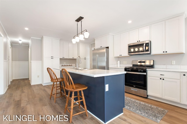 kitchen with a kitchen island with sink, sink, white cabinetry, and stainless steel appliances