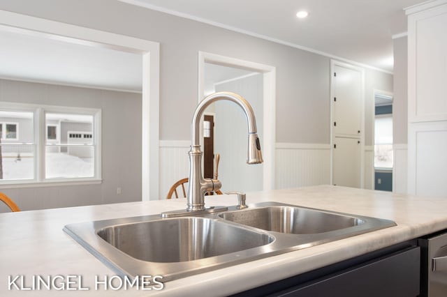 kitchen with white cabinetry, crown molding, and sink