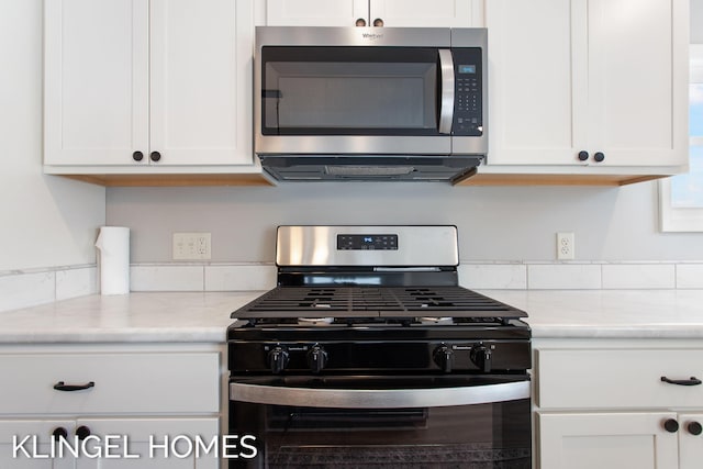 kitchen with white cabinetry, black gas stove, and light stone counters