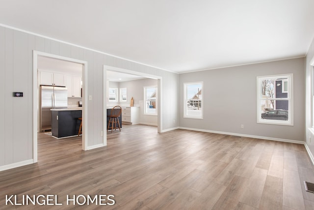 unfurnished room featuring ornamental molding and light hardwood / wood-style flooring