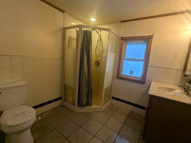 bathroom featuring tile walls, vanity, a textured ceiling, and an enclosed shower