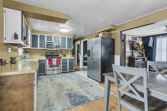 kitchen featuring stainless steel appliances, sink, ceiling fan, and light hardwood / wood-style flooring