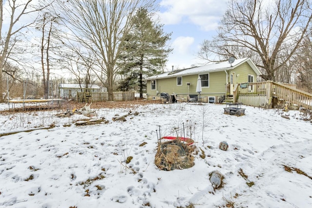 yard layered in snow with a trampoline and a wooden deck