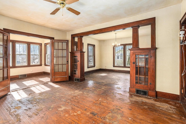 unfurnished dining area with dark hardwood / wood-style flooring and ceiling fan with notable chandelier