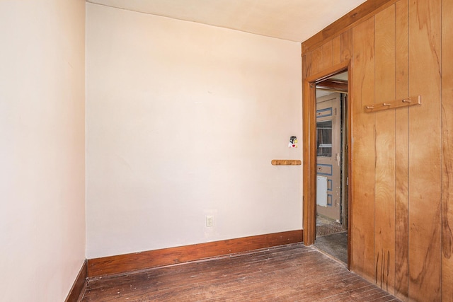 empty room with dark wood-type flooring and wood walls