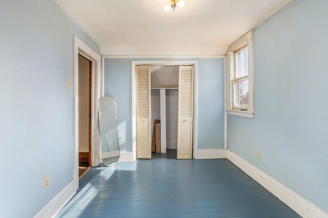 unfurnished bedroom with dark hardwood / wood-style flooring and a closet