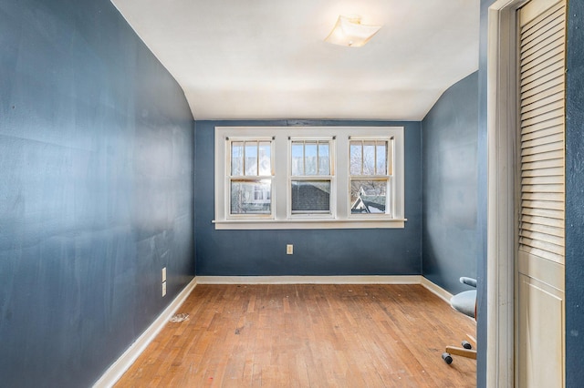 spare room featuring vaulted ceiling and light hardwood / wood-style floors