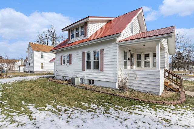 view of snowy exterior featuring cooling unit, a yard, and covered porch