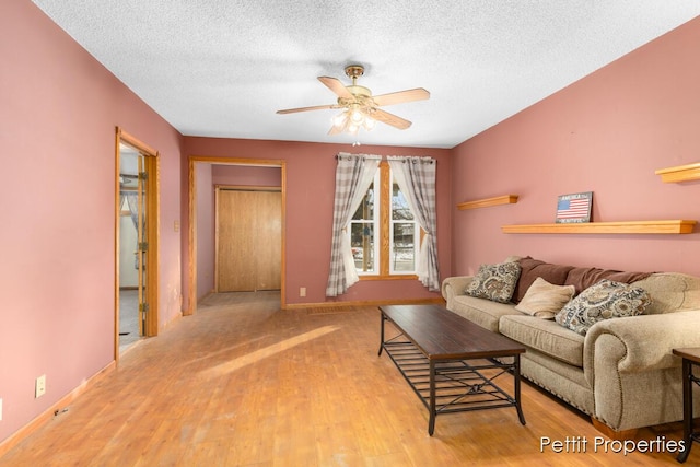 living room featuring ceiling fan, a textured ceiling, and light hardwood / wood-style floors