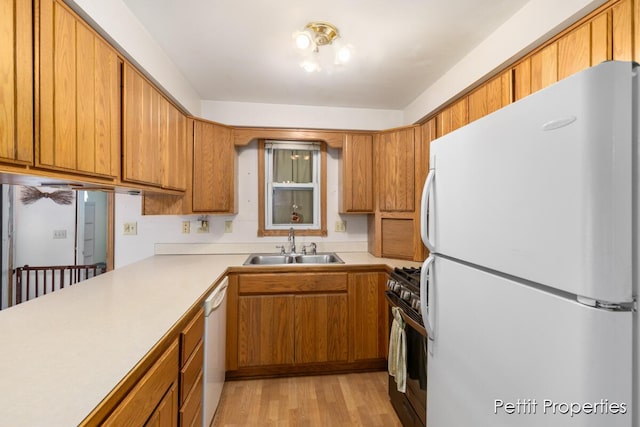 kitchen featuring sink, white appliances, light hardwood / wood-style flooring, and kitchen peninsula