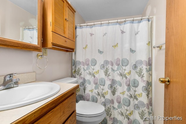 bathroom featuring vanity, curtained shower, and toilet