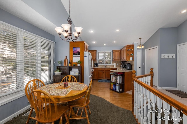 dining room with lofted ceiling, sink, a notable chandelier, and light hardwood / wood-style floors