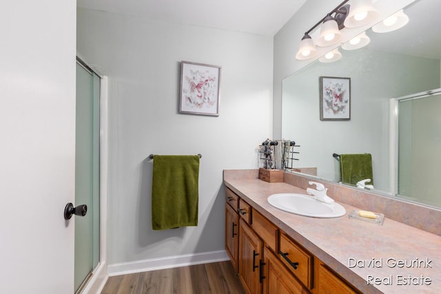 bathroom with hardwood / wood-style flooring, vanity, and a shower with shower door