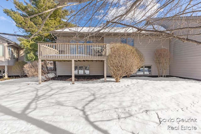 snow covered back of property with a deck