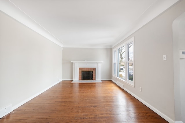 unfurnished living room featuring ornamental molding, wood-type flooring, and a fireplace