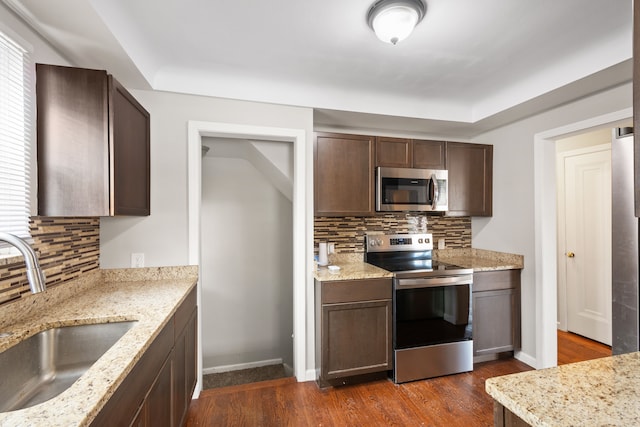 kitchen with appliances with stainless steel finishes, light stone countertops, and sink